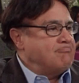 A Man In A Suit And Tie Is Wearing Glasses And Making A Funny Face . GIF