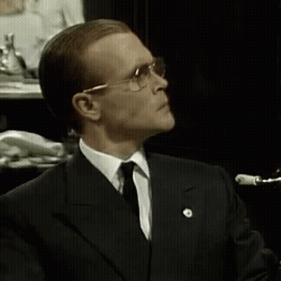 A Man In A Suit And Tie Is Wearing Glasses GIF