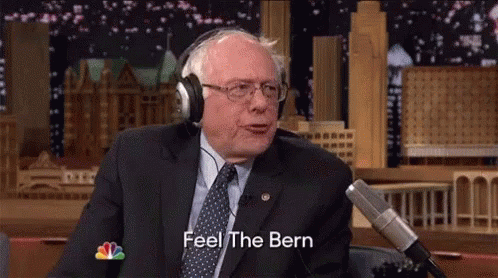 A Man In A Suit And Tie Is Wearing Headphones And Saying Feel The Bern GIF