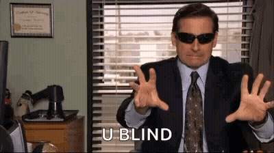 A Man In A Suit And Tie Is Wearing Sunglasses And Making A Gesture . GIF