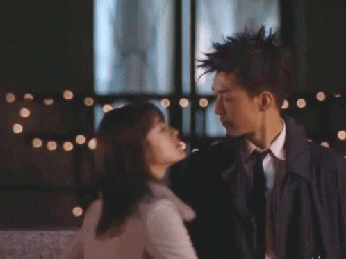 A Man In A Suit And Tie Kisses A Woman GIF