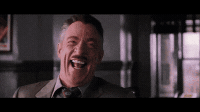 A Man In A Suit And Tie Laughs With His Mouth Open GIF