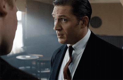 A Man In A Suit And Tie Looks At Another Man GIF