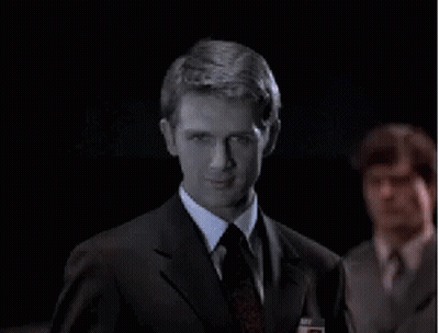 A Man In A Suit And Tie Looks At The Camera GIF