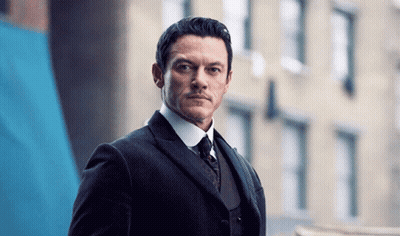 A Man In A Suit And Tie Looks At The Camera GIF