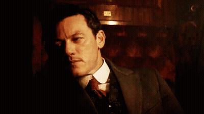 A Man In A Suit And Tie Looks Down At Something GIF