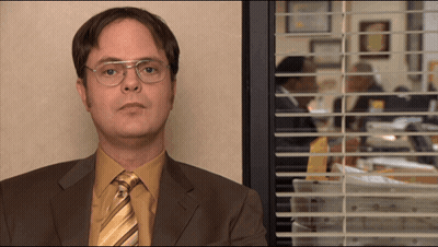 A Man In A Suit And Tie Looks Out A Window GIF