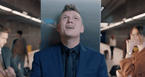 A Man In A Suit And Tie Looks Up At Something GIF