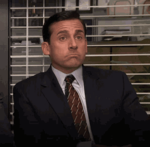 A Man In A Suit And Tie Making A Face GIF