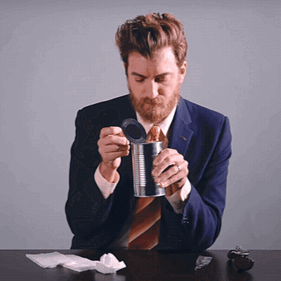A Man In A Suit And Tie Opens A Can GIF