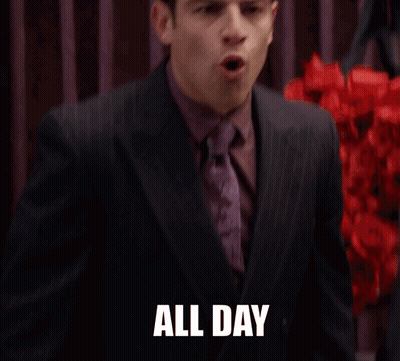 A Man In A Suit And Tie Says " All Day " In Front Of Red Flowers GIF