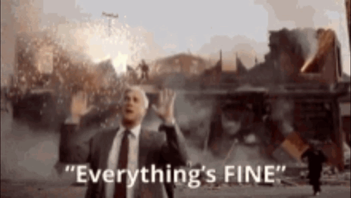 A Man In A Suit And Tie Says " Everything 'S Fine " In Front Of A Burning Building GIF