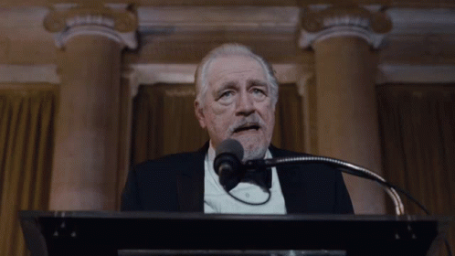 A Man In A Suit And Tie Says " I 'M Back " GIF