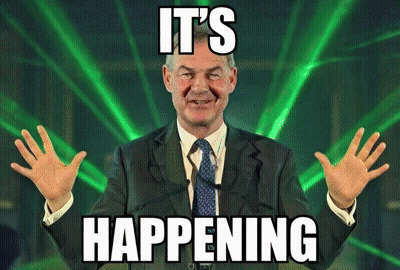 A Man In A Suit And Tie Says It 'S Happening In Front Of A Green Light GIF