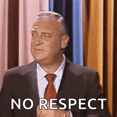 A Man In A Suit And Tie Says " No Respect " In Front Of A Curtain GIF