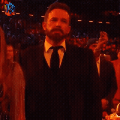A Man In A Suit And Tie Says Wey Ya In Front Of A Crowd Of People GIF
