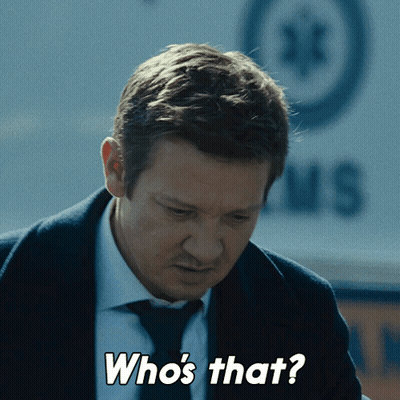 A Man In A Suit And Tie Says " Who 'S That " In Front Of An Ambulance GIF