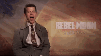 A Man In A Suit And Tie Screams In Front Of A Rebel Moon Part One Poster GIF