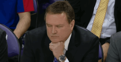 A Man In A Suit And Tie Sits In A Purple Chair GIF