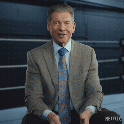 A Man In A Suit And Tie Sits In Front Of A Netflix Logo GIF