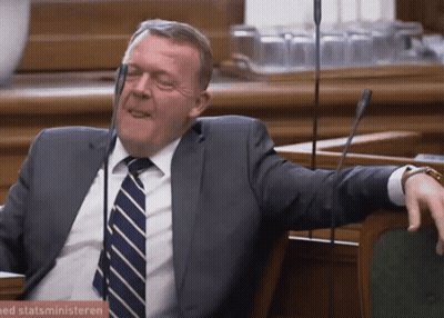 A Man In A Suit And Tie Sits In Front Of A Sign That Says Statsministeren On It GIF