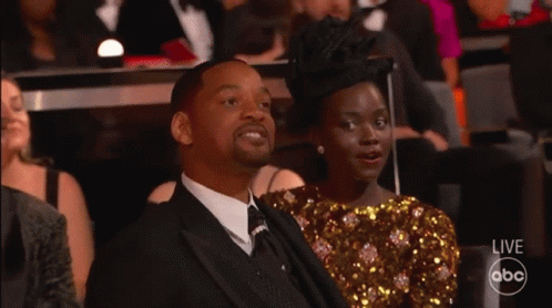 A Man In A Suit And Tie Sits Next To A Woman In A Sequined Dress While Watching A Live Abc Broadcast GIF