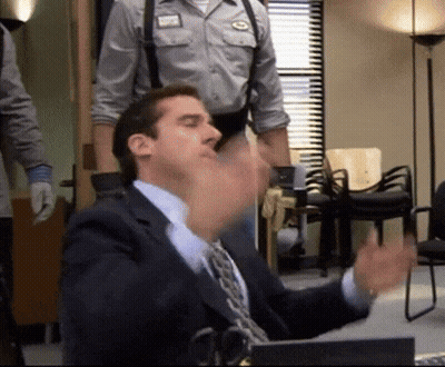 A Man In A Suit And Tie Sitting At A Desk GIF