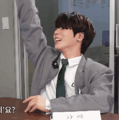 A Man In A Suit And Tie Sitting At A Desk GIF