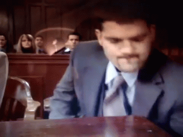 A Man In A Suit And Tie Sitting At A Table GIF