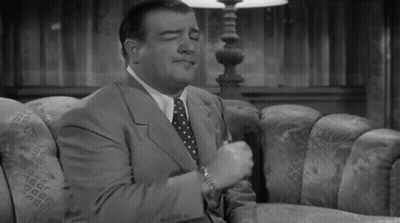A Man In A Suit And Tie Sitting On A Couch GIF