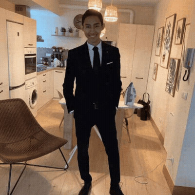 A Man In A Suit And Tie Smiles In A Kitchen GIF