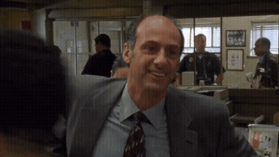 A Man In A Suit And Tie Smiles In A Room GIF