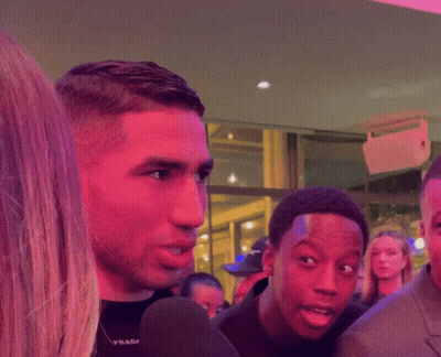 A Man In A Suit And Tie Smiles While Standing Next To Another Man GIF