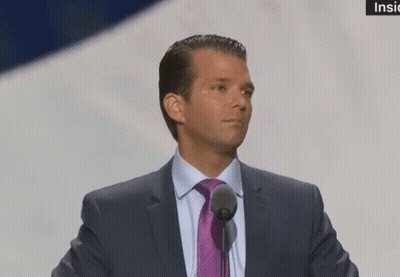 A Man In A Suit And Tie Speaking Into A Microphone . GIF