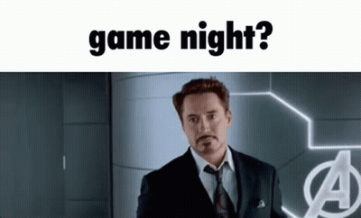 A Man In A Suit And Tie Standing In Front Of A Sign That Says Game Night GIF