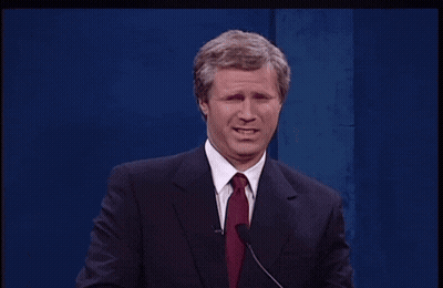 A Man In A Suit And Tie Stands At A Podium GIF
