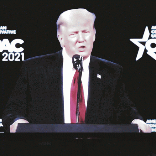 A Man In A Suit And Tie Stands At A Podium With The Word Sorry On It GIF