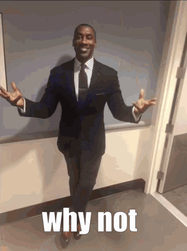 A Man In A Suit And Tie Stands In A Hallway With His Arms Outstretched And The Words Why Not Below Him GIF
