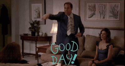 A Man In A Suit And Tie Stands In A Living Room With The Words Good Day Written On The Wall GIF
