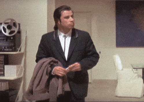A Man In A Suit And Tie Stands In A Room GIF