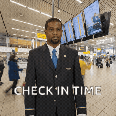A Man In A Suit And Tie Stands In An Airport With The Words Check In Time Above Him GIF