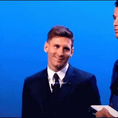 A Man In A Suit And Tie Stands In Front Of A Blue Wall GIF