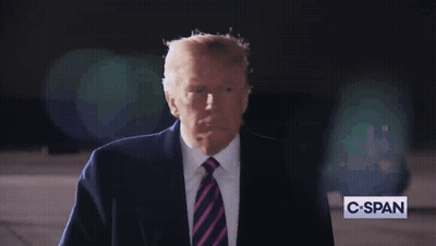 A Man In A Suit And Tie Stands In Front Of A C-Span Sign GIF