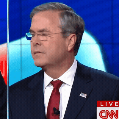 A Man In A Suit And Tie Stands In Front Of A Cnn Live Screen GIF