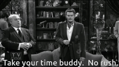 A Man In A Suit And Tie Stands In Front Of A Couch With The Words Take Your Time Buddy No Rush Below Him GIF