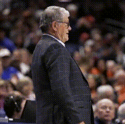 A Man In A Suit And Tie Stands In Front Of A Crowd GIF