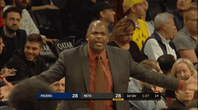 A Man In A Suit And Tie Stands In Front Of A Crowd Watching A Basketball Game Between Pacers And Nets GIF