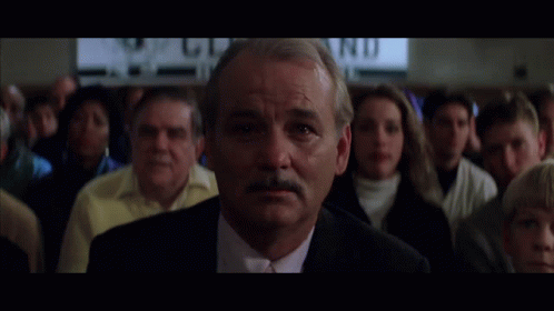 A Man In A Suit And Tie Stands In Front Of A Crowd With A Sign In The Background That Says " Wd " GIF