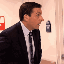 A Man In A Suit And Tie Stands In Front Of A Door With A Sign On It That Says Emergency Room GIF