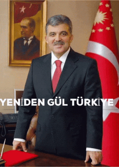 A Man In A Suit And Tie Stands In Front Of A Flag With The Words Yeniden Gul Turkey Written Below Him GIF